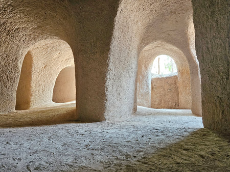 Inside the unique sand temple, rough, textured walls and curved archways bathed in soft natural light.の写真素材