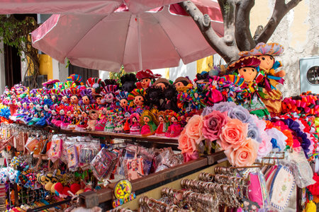 Tlaquepaque, Mexico - October 5 2025: Vibrant Mexican craft stall in Tlaquepaque. Colorful handmade dolls, keychains, and souvenirs displayed under a pink umbrellaのeditorial素材