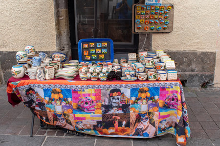 Tlaquepaque, Mexico - October 5 2025: Colorful Mexican artisan pottery, mugs, and souvenirs at a Tlaquepaque street stall. Day of the Dead tablecloth adds cultural richnessのeditorial素材