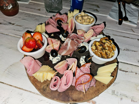 Elegant charcuterie board with a selection of cured meats, fine cheeses, fresh strawberries, pistachios, walnuts, olivesの写真素材