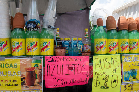 Guadalajara, Mexico - August 30 2025: Street beverage stand with Squirt grapefruit sodas topped with traditional clay pots. Signs for Azulitos Sin Alcohol and Rusas drinksのeditorial素材