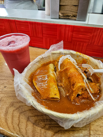 Torta Ahogada and crispy Taco Dorado in red sauce, served in basket with fruit drink on wood. Popular Mexican street foodの写真素材