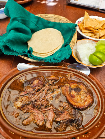 Delicious Mexican Birria stew. Tender, slow-cooked meat in savory broth, served with warm tortillas, onions, and limeの写真素材