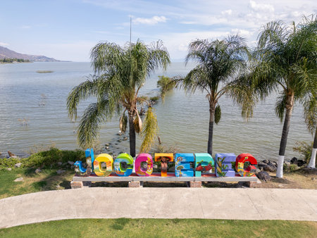 Jocotepec, Mexico - February 22, 2025: Elevated horizontal aerial shot of colorful Jocotepec sign with palm trees by the shore of Lake Chapala in Jaliscoのeditorial素材