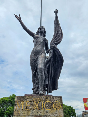 Guadalajara, Mexico - June 22 2025: Close-up of the impressive Motherland Monument in Guadalajara, Mexico, showcasing its details, raised arm, and flag against a cloudy skyのeditorial素材