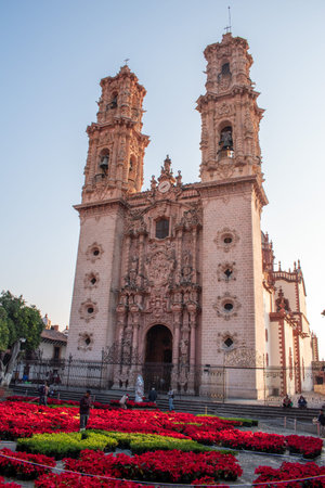 Historic Santa Prisca Church in Taxco, Guerrero, Mexico, adorned with vibrant poinsettias during the holiday seasonのeditorial素材