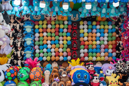 Tlaquepaque, Mexico - June 28 2025: Colorful fair game booth with balloon targets. Abundant plush...