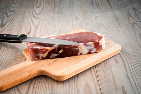 Spanish food - Meat with knife on wooden table 