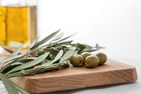 Olive oil with olives and olive branch on wooden board isolated on white backgroundの写真素材