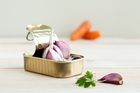 Garlic in tin can with carrots on wooden boardの写真素材