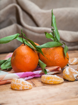 Ripe sweet tangerine with leaves on wooden boardの写真素材