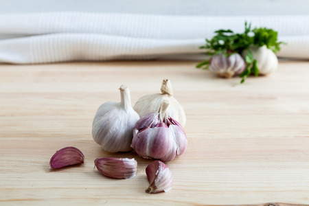 Composition of purple garlic with parsley on wooden boardの写真素材