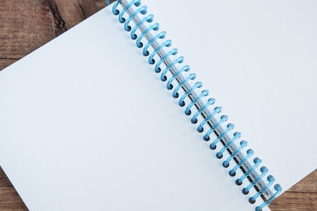Open notepad with empty white pages laying on a wooden tableの写真素材