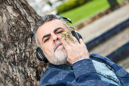 Man with beard listening to music in a parkの写真素材