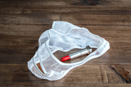 makeup brush and cosmetics with thong on white wooden tableの写真素材
