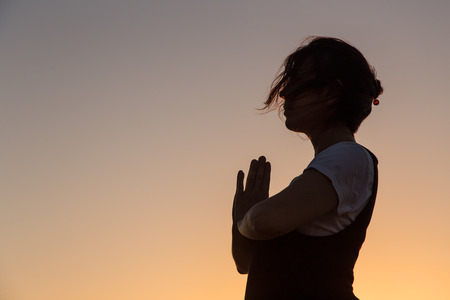 Silhouette young woman practicing yoga on the mediterranean beach at sunset.の写真素材