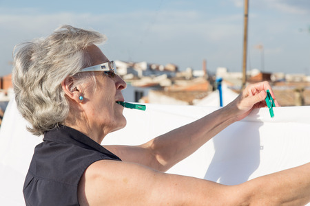 Senior woman hanging out the washing on the terraceの写真素材