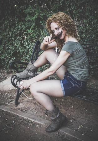 Attractive blond girl listening to music on the parkの写真素材