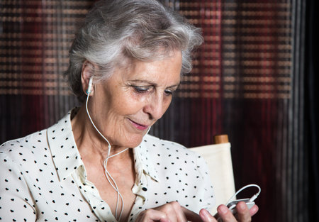 Portrait of a happy senior woman listening to music on mobile