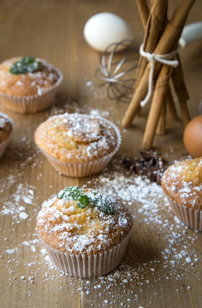 Homemade muffins with star anise, cinnamon and mint on old wooden tableの写真素材