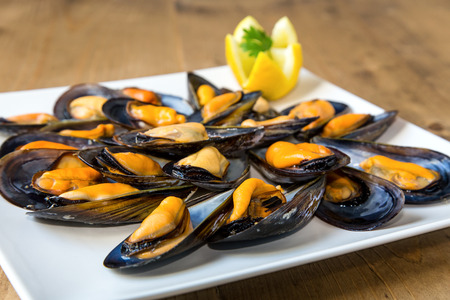 Steamed mussels with lemon and parsley on old wooden tableの写真素材