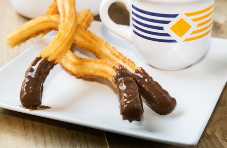 Churros with hot chocolate and sugar on old wooden tableの写真素材