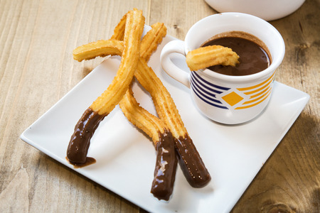 Churros with hot chocolate and sugar on old wooden tableの写真素材