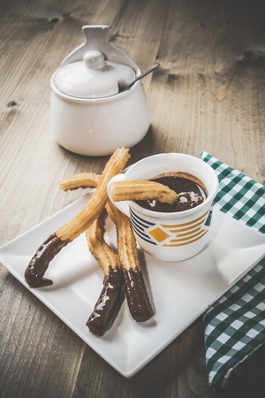 Churros with hot chocolate and sugar on old wooden tableの写真素材