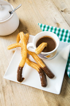 Churros with hot chocolate and sugar on old wooden tableの写真素材