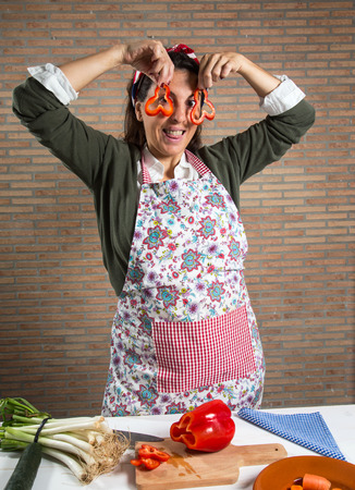 Woman cutting vegetables in wooden table in the kitchenの写真素材