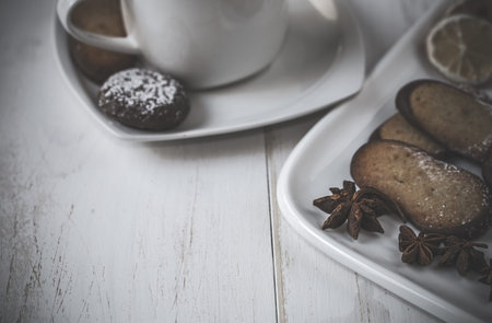 Assorted Cookies and coffee on wooden table with cinnamon and lemon orangeの写真素材