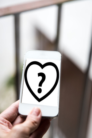 Mobile concept question: woman hands holding a mobile phone with the display of a question markの写真素材