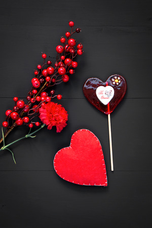 Valentines day with hearts and red flowers on black wooden tableの写真素材