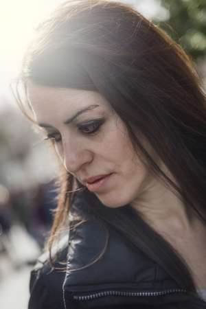 Portrait of calm adult woman looking away while standing outdoors. Bokeh.の写真素材