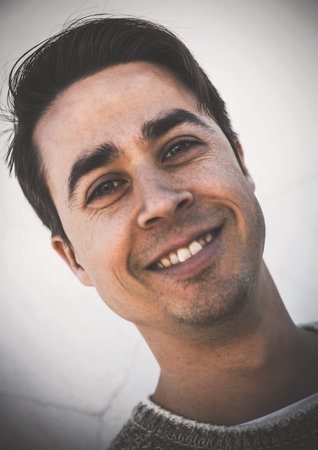 Headshot of attractive man with dark hair smiling at camera