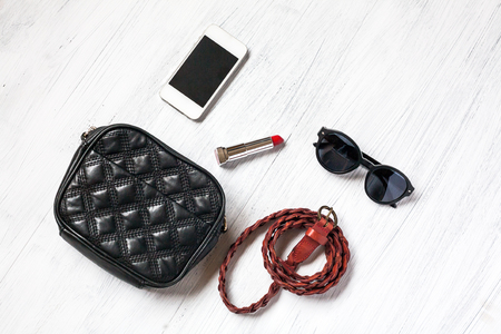 Close-up of Clothing and fashion accessories on wooden table,bag, belts, sunglasses, telephone, mobile phone, lipstickの写真素材
