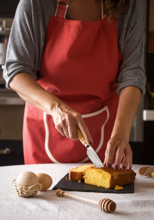 Woman's arms slicing cake on black board in morningの写真素材