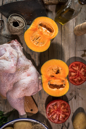 Uncooked spiced chicken and vegetables on kitchen table.From aboveの写真素材