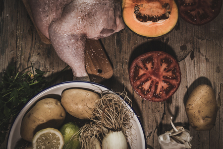 Uncooked spiced chicken and vegetables on kitchen table.From aboveの写真素材