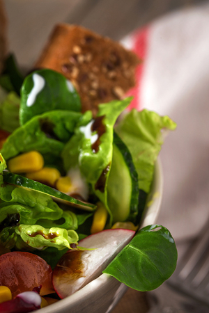 Fresh vegetarian salad in bowl  with fork in close-upの写真素材