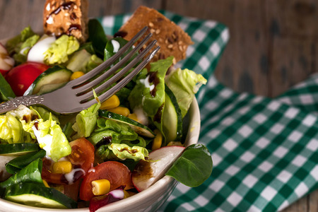 Fresh vegetarian salad in bowl  with fork in close-upの写真素材