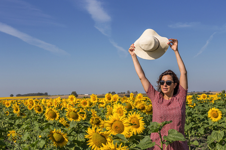 back view of  adult woman in sunhat in sunflower fieldの写真素材
