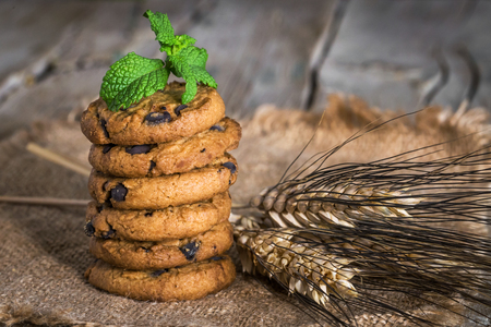 freshly baked chocolate chip cookies on rustic old wooden tableの写真素材