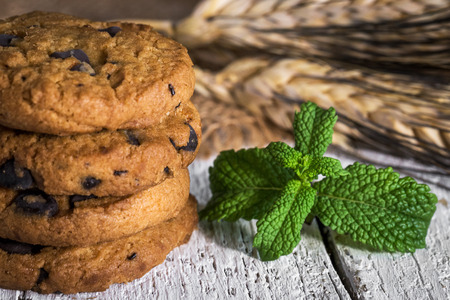 freshly baked chocolate chip cookies on rustic old wooden tableの写真素材