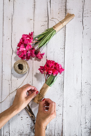 Woman hands making bouquets on old white wooden tableの写真素材