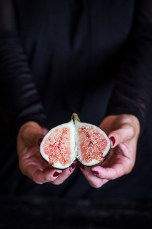 sweet fig in woman hand on black backgroundの写真素材