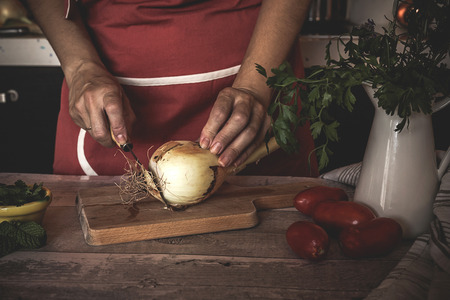 unrecognizable Woman cutting vegetables on wooden table in the kitchenの写真素材