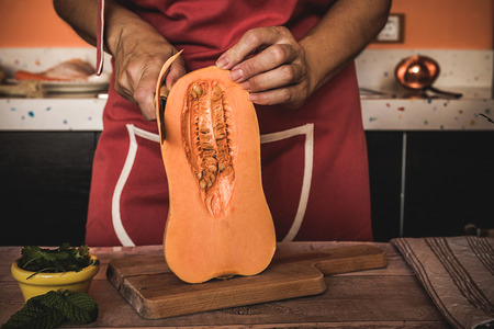 unrecognizable Woman cutting vegetables on wooden table in the kitchenの写真素材