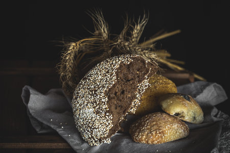Different fresh bread on old wooden table with flour and napkin