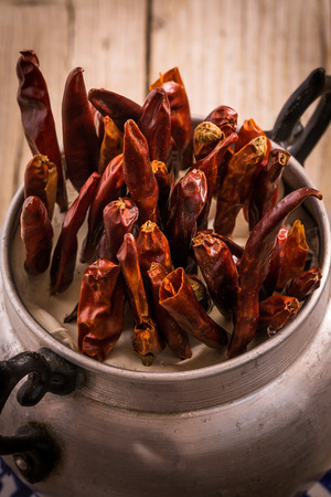 spicy red chillies in cup on old wooden tableの写真素材